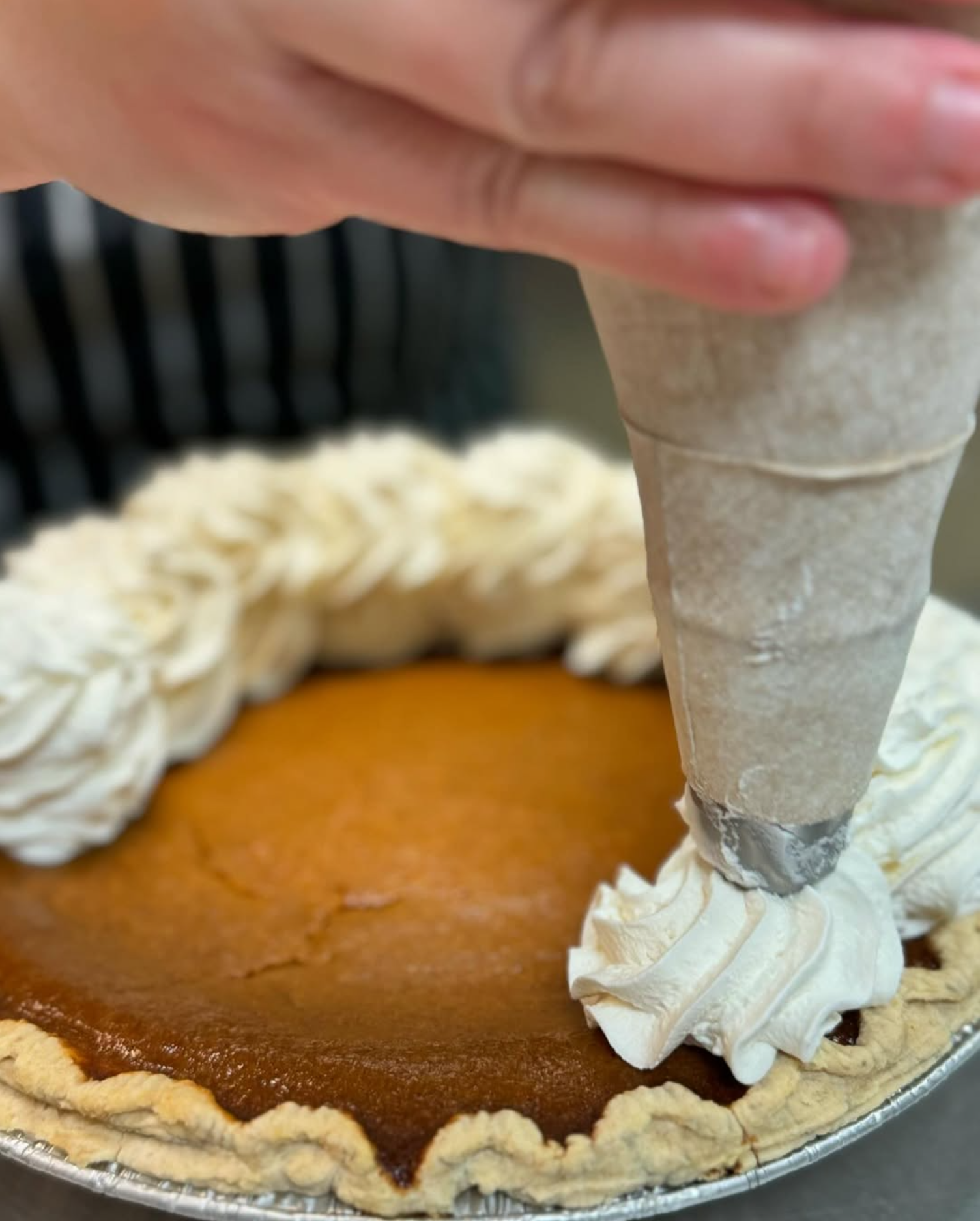 Pastry chef putting the finishing touches on a pumpkin pie